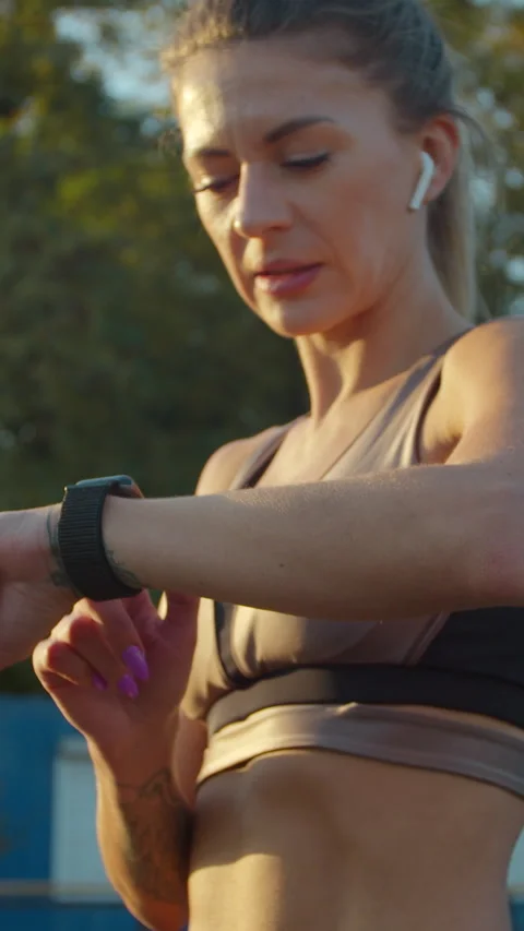 Vertical video. Sportswoman using smart watch and Listening to Music Видео 342912591
