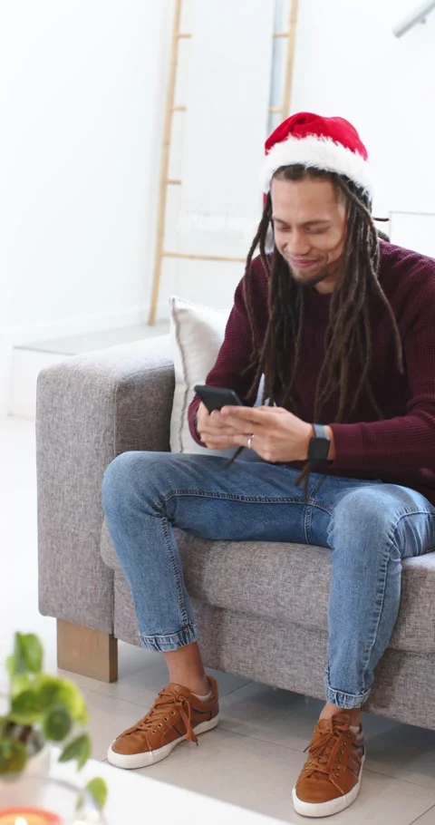 Vertical video: Spotting phone ping, man in Santa hat tapping, scrolling on Stock Footage 345395499