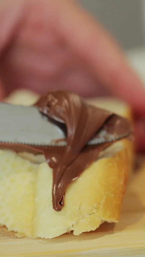 Vertical video. Spread chocolate butter on bread while cooking breakfast Stock Footage 345703018