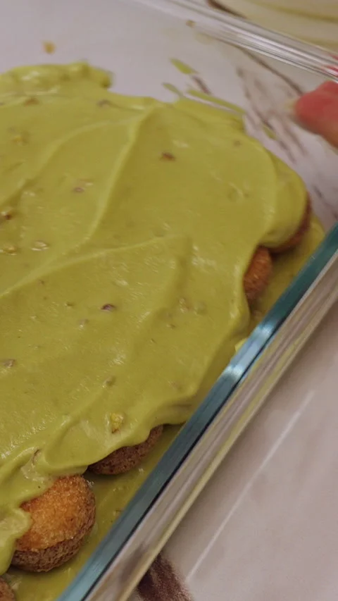 Vertical video. Spreading Green Cream Smoothly Over Savoiardi Biscuits With Spat Stock Footage 326660890