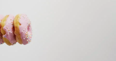 Vertical video of stack of donuts with pink frosting on grey background Stock Footage 207399620