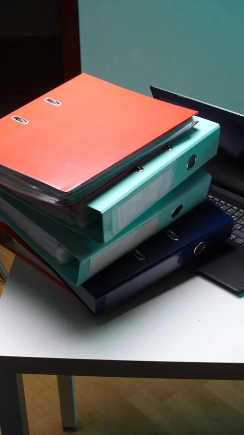 Vertical video stack of various colored ring binders containing important Stock Footage 346250739
