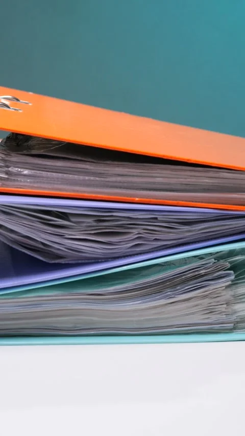 Vertical video stacked ring binders overflowing with various papers Stock Footage 342763341