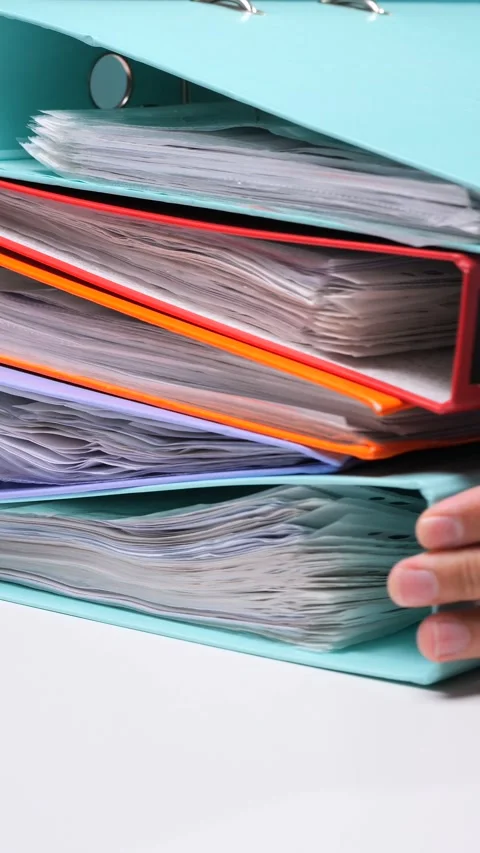 Vertical video stacked ring binders in various colors holding numerous Stock Footage 342766637