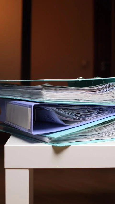 Vertical video stacked ring binders holding numerous documents and paperwork on Stock Footage 347238451