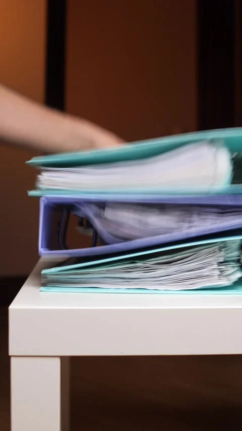Vertical video stacked ring binders overflowing with papers and folders Stock Footage 347240190
