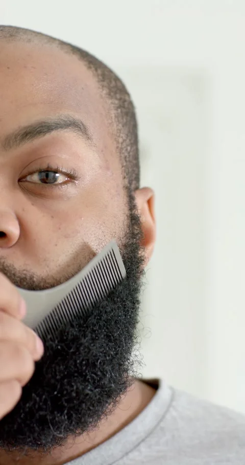 Vertical video: Starting with comb, African American man grooming beard at home, Stockbeeldmateriaal 345397275