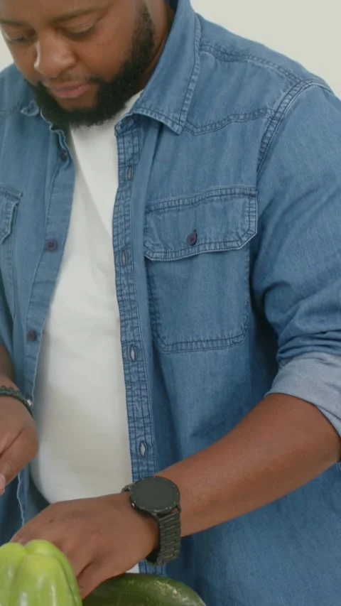 Vertical video: Starting prep, slicing cucumber, man denim shirt packing at Stock Footage 348636305