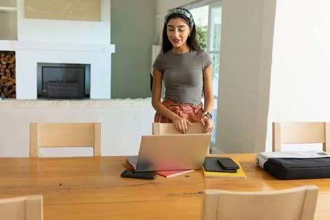 Vertical video: Starting work Indian woman moving chair, checking laptop at home Stock Photos