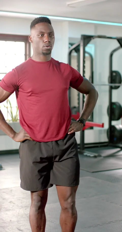 Vertical video: Stepping on red band in gym, African American man lifting knee, Stock Footage 346721214
