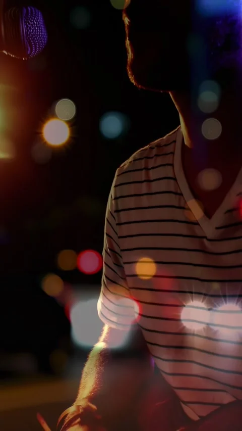Vertical video: Strumming man in striped tee playing guitar as camera pulling at Stock Footage 334549625