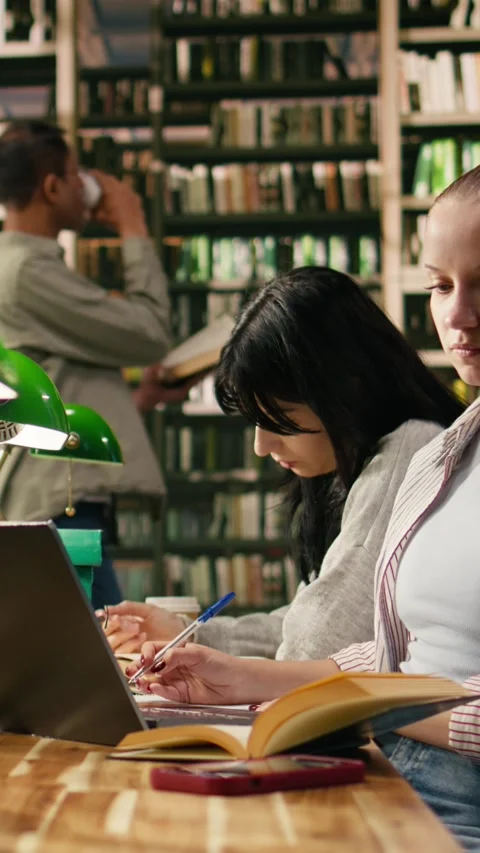 Vertical Video Student in university library distracted by smartphone Stock Footage 336379112