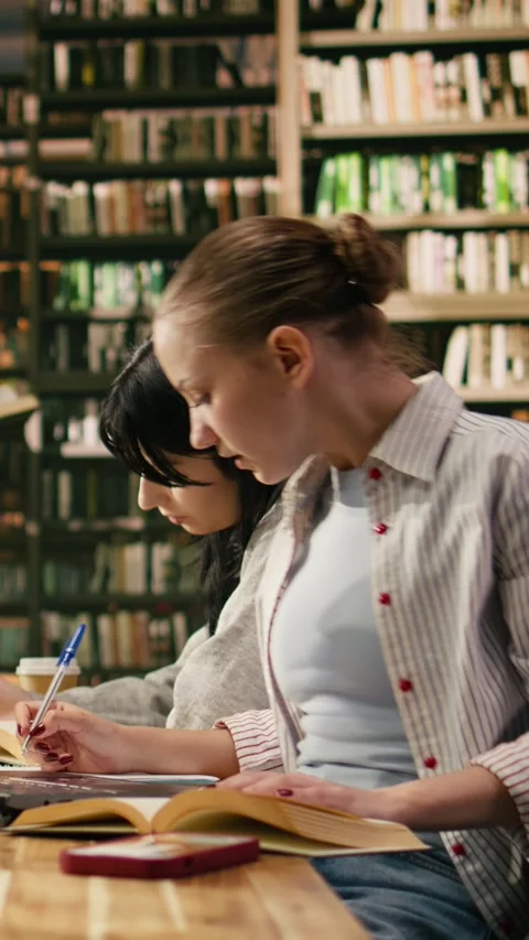 Vertical Video Student uses laptop and book losing concentration when mobile Stock Footage 336378977
