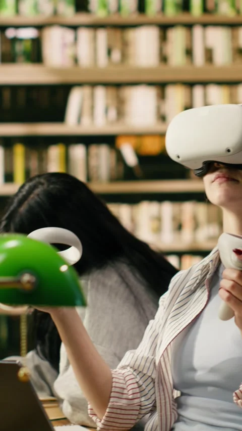 Vertical Video Student using virtual reality headset and hand controllers at Stock Footage 336380199