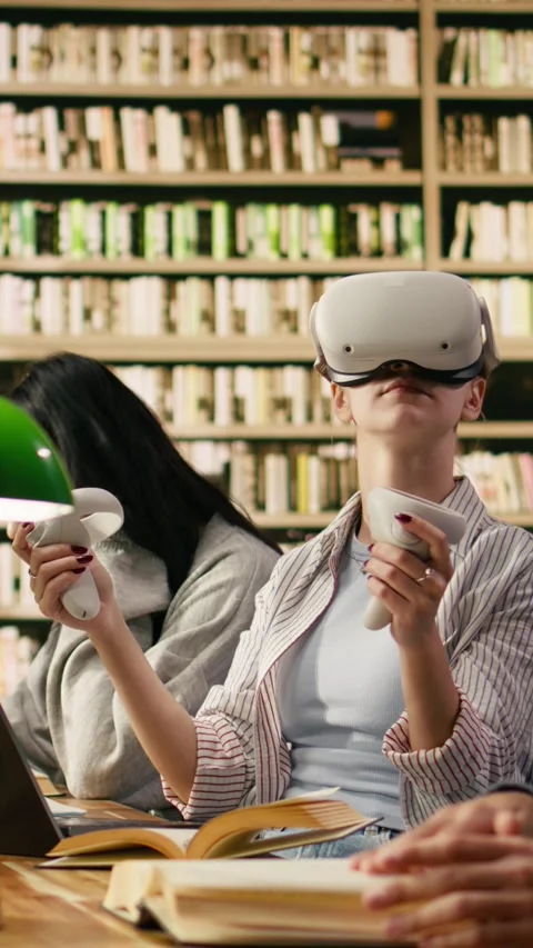 Vertical Video Student wears VR glasses and holds controllers in university Stock Footage 336379180