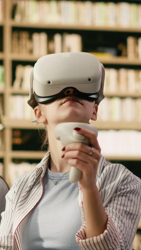 Vertical Video Student wears VR glasses and holds controllers in university Stock Footage 336380174