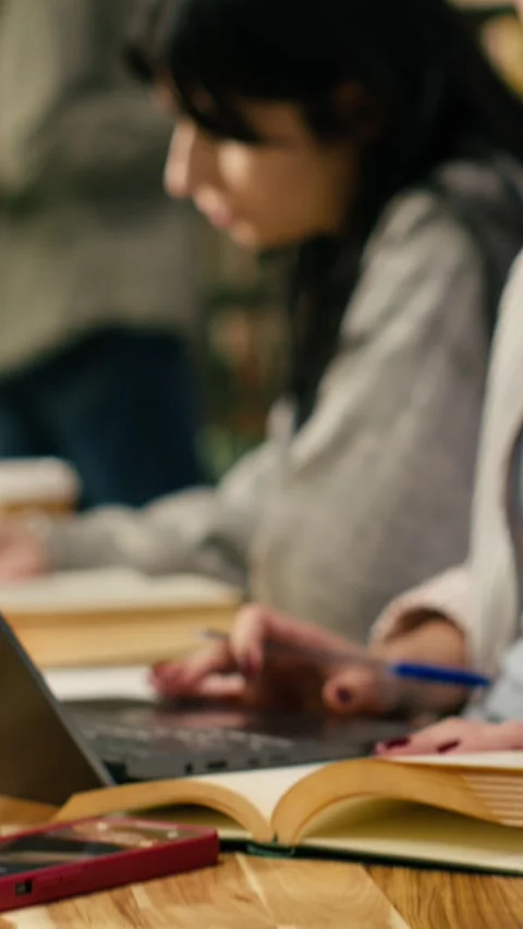 Vertical Video Student writing on textbook and loses focus after receiving phone Stock Footage 336380099