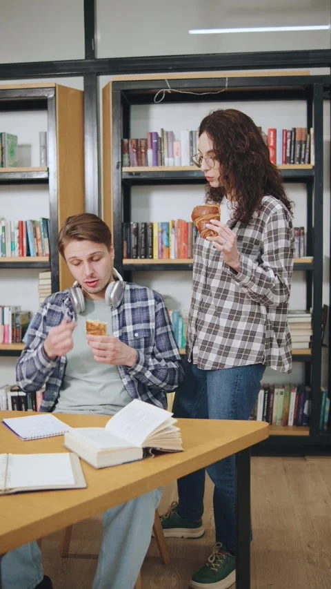 Vertical video of Students studying together in a library while enjoying snacks Stock Footage 308668529