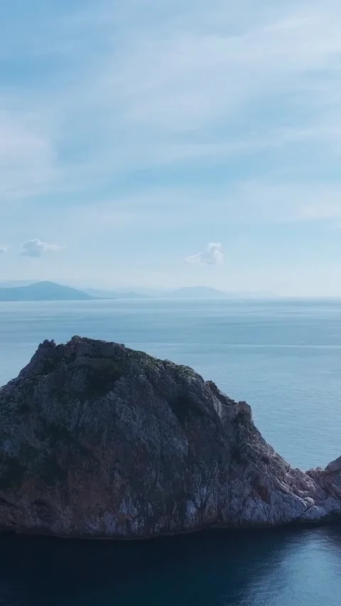 Vertical Video of a Stunning Cliff Emerging From the Sea, With Clear Azure Water Stock-Footage 301339314