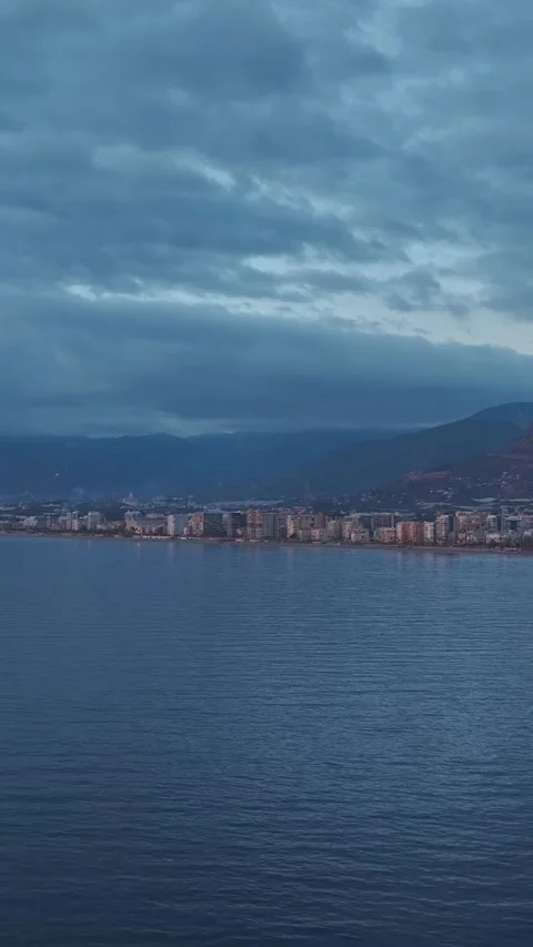 Vertical Video: Stunning view of a cityscape from the sea at sunset, with Stock Footage 297656598