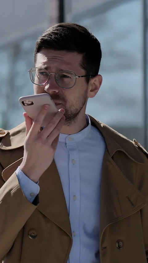 Vertical video. Stylish man making voice message or using virtual assistant app Stock Footage 345234590