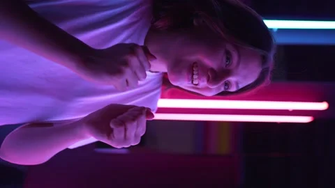 Vertical video - success and a winner. Amazed young woman in neon lamps Stock Footage 152565645