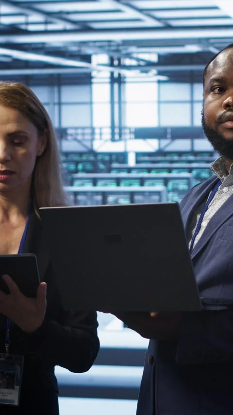 Vertical video Supervisor in server farm overseeing engineer fixing network Stockbeeldmateriaal 277858240