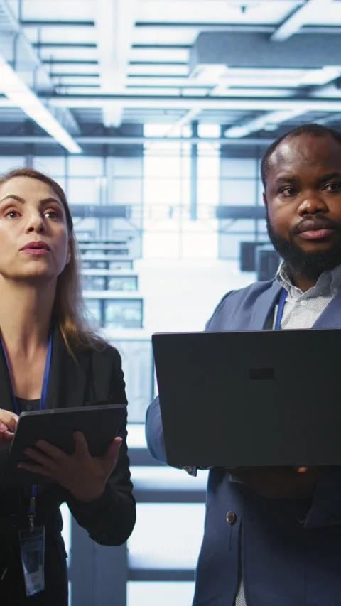 Vertical video Supervisor in server farm overseeing engineer fixing network Stockbeeldmateriaal 277858306