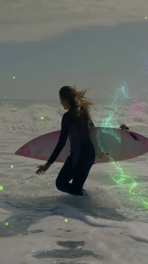 Vertical video: Surfer wading as waves break, bracing pink board, sparkles 스톡 동영상 334541047