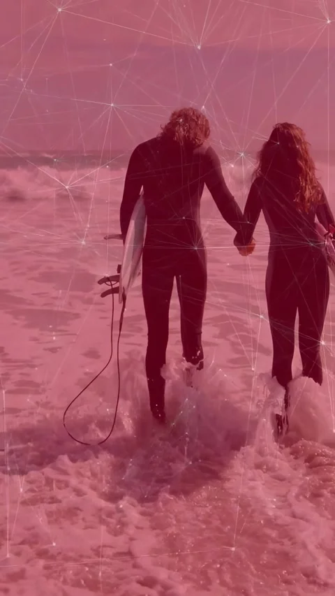 Vertical video: Surfers carrying board holding hands stepping into surf, red net 스톡 동영상 334540458