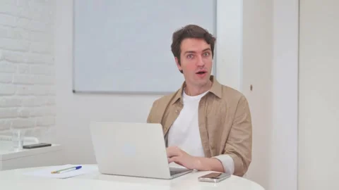 Vertical Video, Surprised Young Man Looking at Camera while Working on Laptop Stock Footage 312914350
