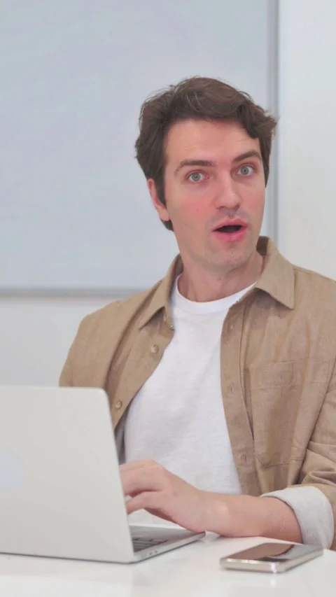 Vertical Video, Surprised Young Man Looking at Camera while Working on Laptop Stock Footage 318048177