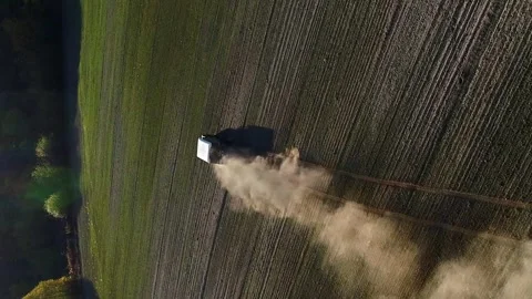 Vertical video. An SUV is driving on a plowed green field. View from a drone Stock-Footage 254488482