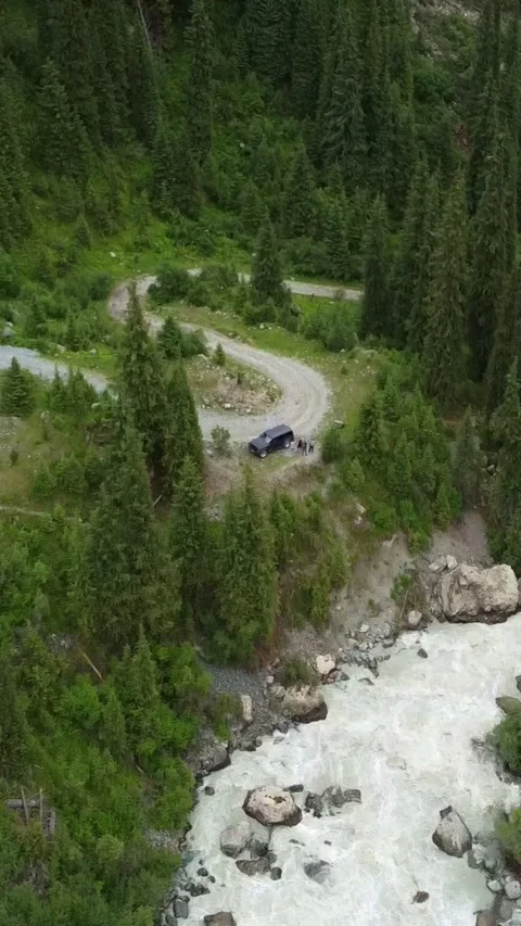 Vertical video: SUV Parked on S-Curve Serpentine Road by Rushing River Video stock 332205313