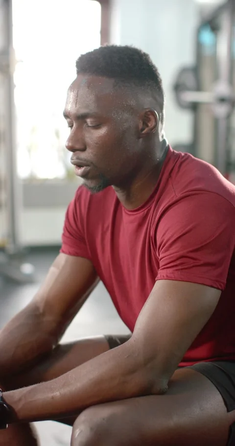 Vertical video: Sweat beading urging African American man wiping brow at gym Stock Footage 345040307