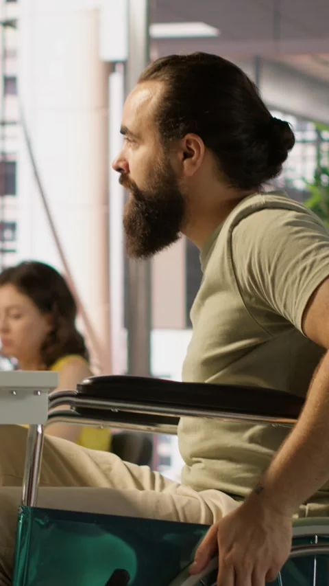 Vertical video T worker with disability in wheelchair in office working at Stock Footage 319489006