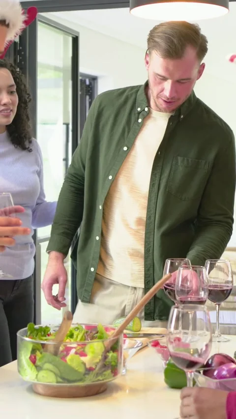Vertical video: Talking host in green shirt leading friends serving salad at Stock Footage 348571464