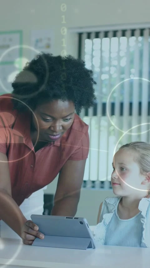 Vertical video: Teacher holding tablet guiding pupil, tapping, icons and code Stock Footage 334128165