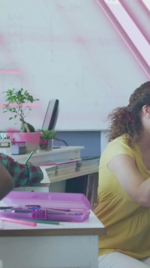 Vertical video: Teacher leaning, helping student writing in class, pink overlay Stock Footage 331238104