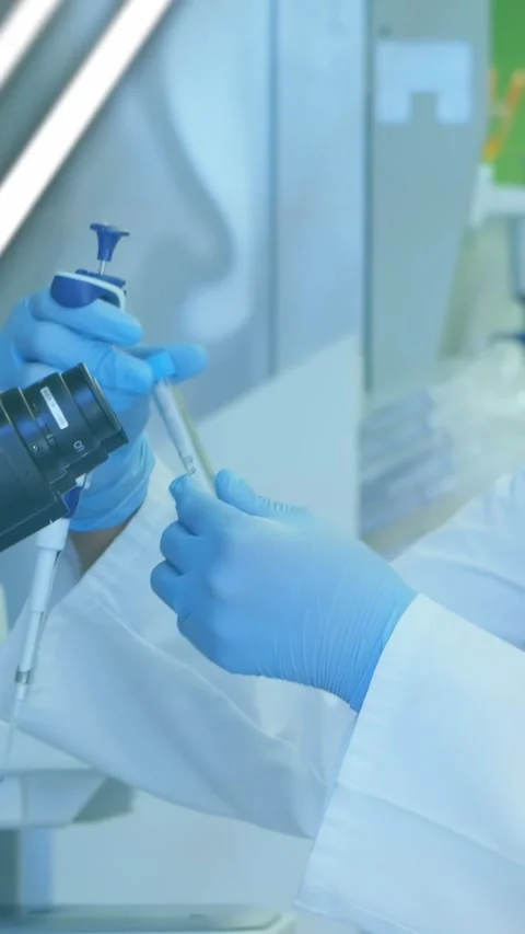 Vertical video: Tech aligning pipette, drawing sample by scope for assay while Stock Footage 330509878