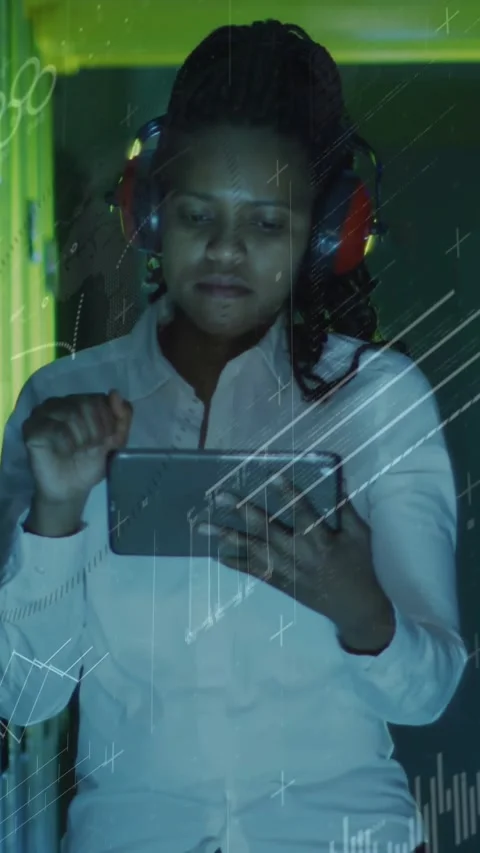 Vertical video: Tech pointing up, donning red muffs and tapping tablet for Stock Footage 331237940