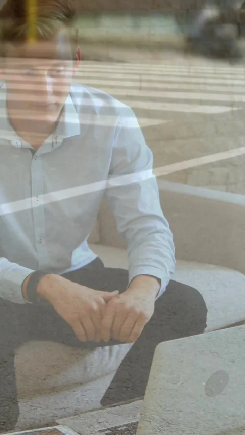 Vertical video: Tech worker sitting by window reaching laptop to check work Stock Footage 334540846
