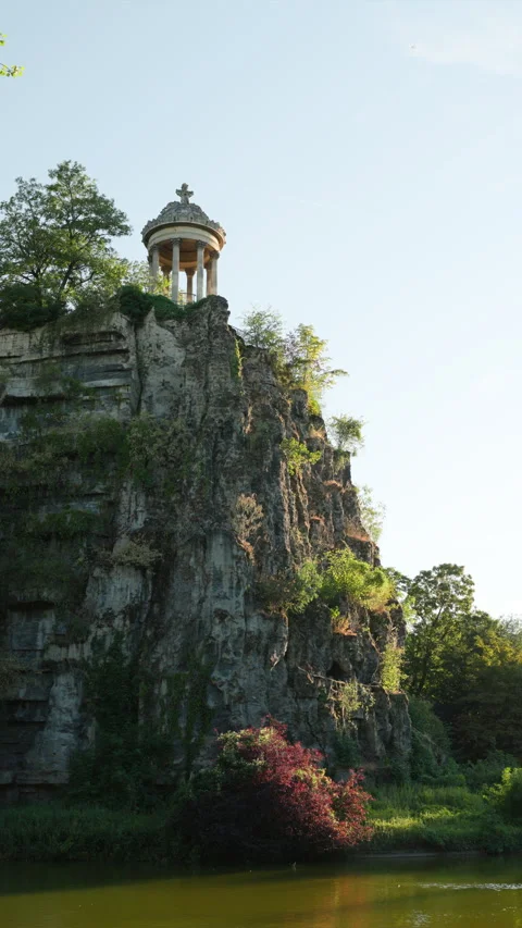 Vertical Video of Temple de la Sibylle on Cliff with Lake and Red Bush at Parc d Stock Footage 338383339