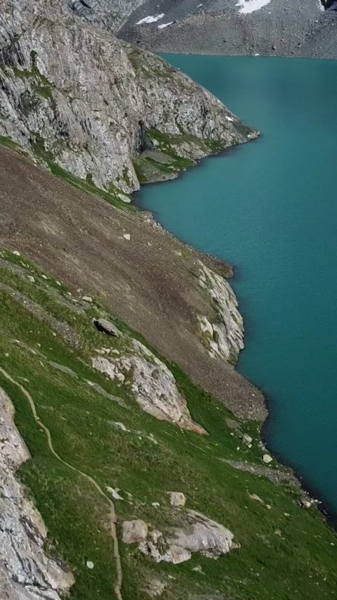Vertical video: Tiny Hikers on Narrow Cliff Trail by Turquoise Lake Aerial Stock Footage 332205283