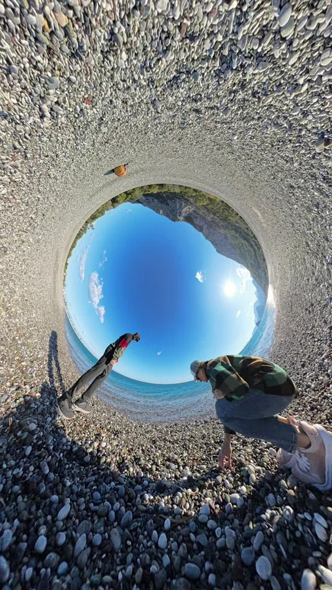 Vertical video. A tiny planet effect capturing a couple throwing stones into the Stock Footage 294433956