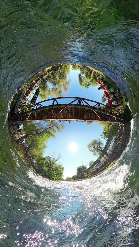 Vertical video. A Tiny Planet view of a wooden bridge over a river, surrounded 스톡 동영상 289794196