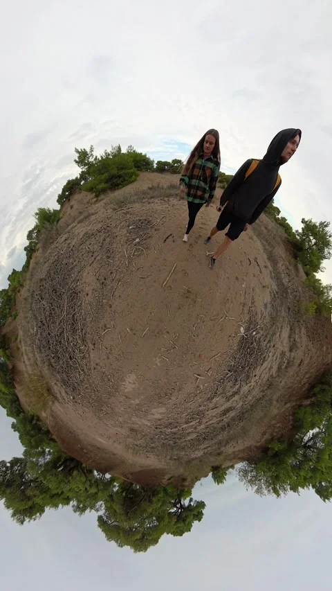 Vertical video. A tiny planet view featuring a man and a woman walking on sandy 스톡 동영상 293086396