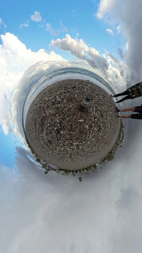 Vertical video. Tiny Planet view of a pebble beach featuring a balanced stone Vídeos de archivo 293281876