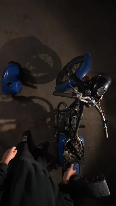 Vertical video Tired man sitting in a garage, removing work gloves and taking a Stock Footage 342764162
