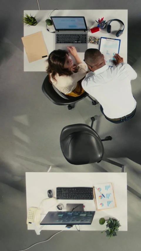 Vertical Video Top down view zoom in of staff consulting on project reports and Stock Footage 319806947
